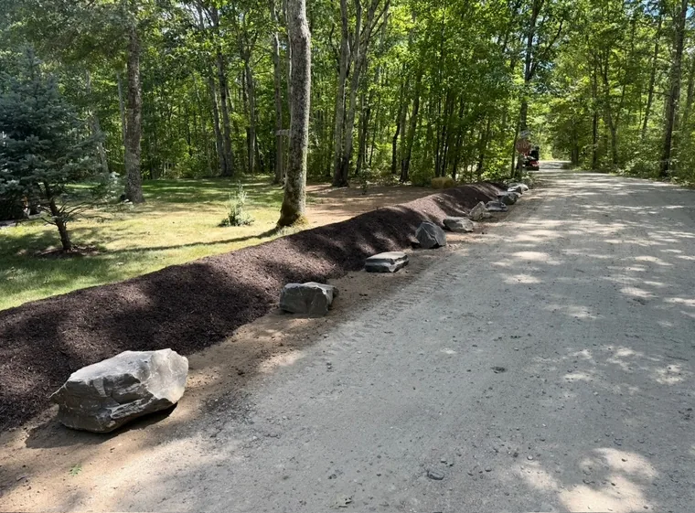 Roadside bank mulched and edged with boulders