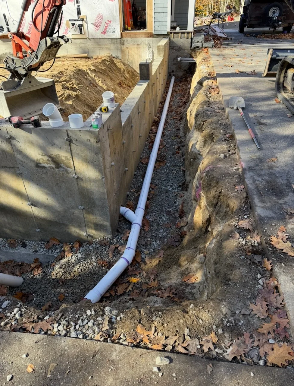 Perimeter foundation drain bedded in stone against the wall
