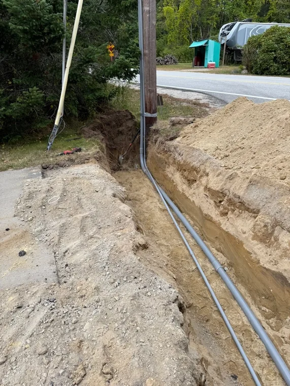 Conduit run in an open trench alongside the road to the utility pole
